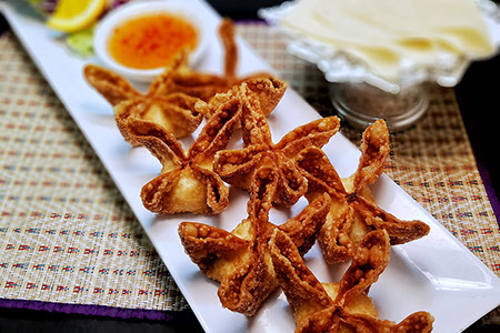 Crab rangoons on a plate with dipping sauce